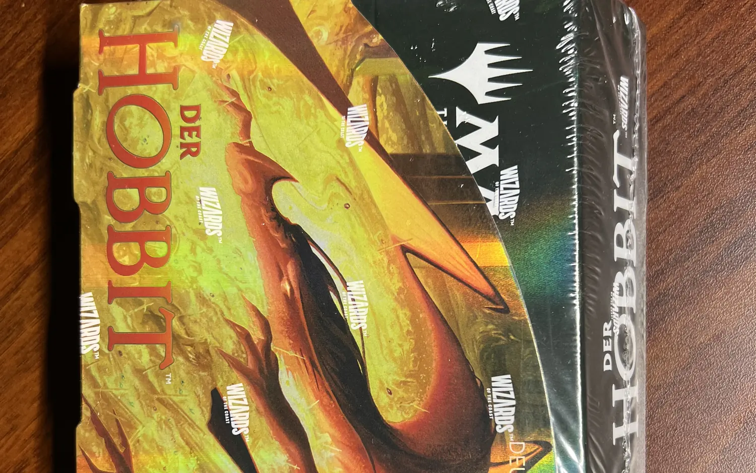Ein versiegeltes Display mit Sammler-Boostern zum Hobbit für Magic: The Gathering, auf dem Aufdruck ein Drache über einer Wiese.