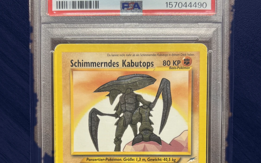 PSA-Slab einer deutschen Karte Schimmerndes Kabutops, am unteren Rand des Etiketts der Strichcode und die Zertifikatsnummer 157044490