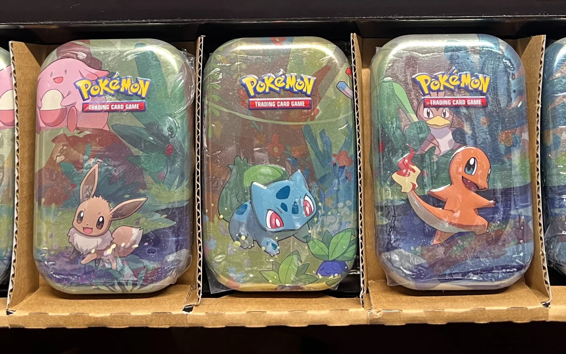 Pokémon-Mini-Tins stehen aufgereiht in einem offenen Umkarton aus Pappe.