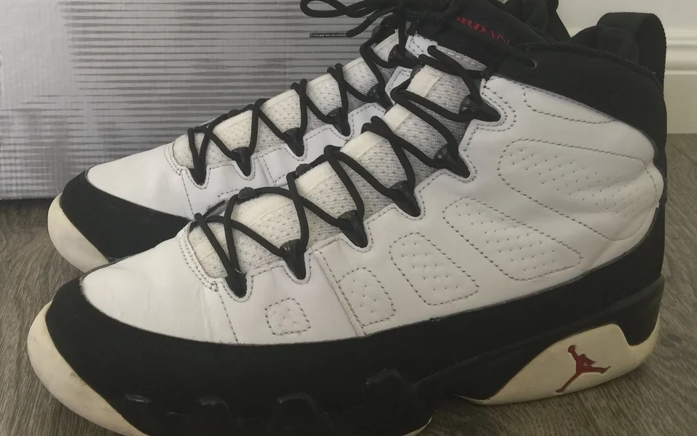Ein weißer Air Jordan IX mit schwarzen Schnürsenkeln in Nahaufnahme